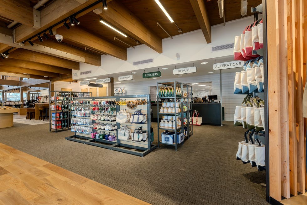 Interior view of a retail store showing shelving units with various merchandise and service areas indicated by signs.