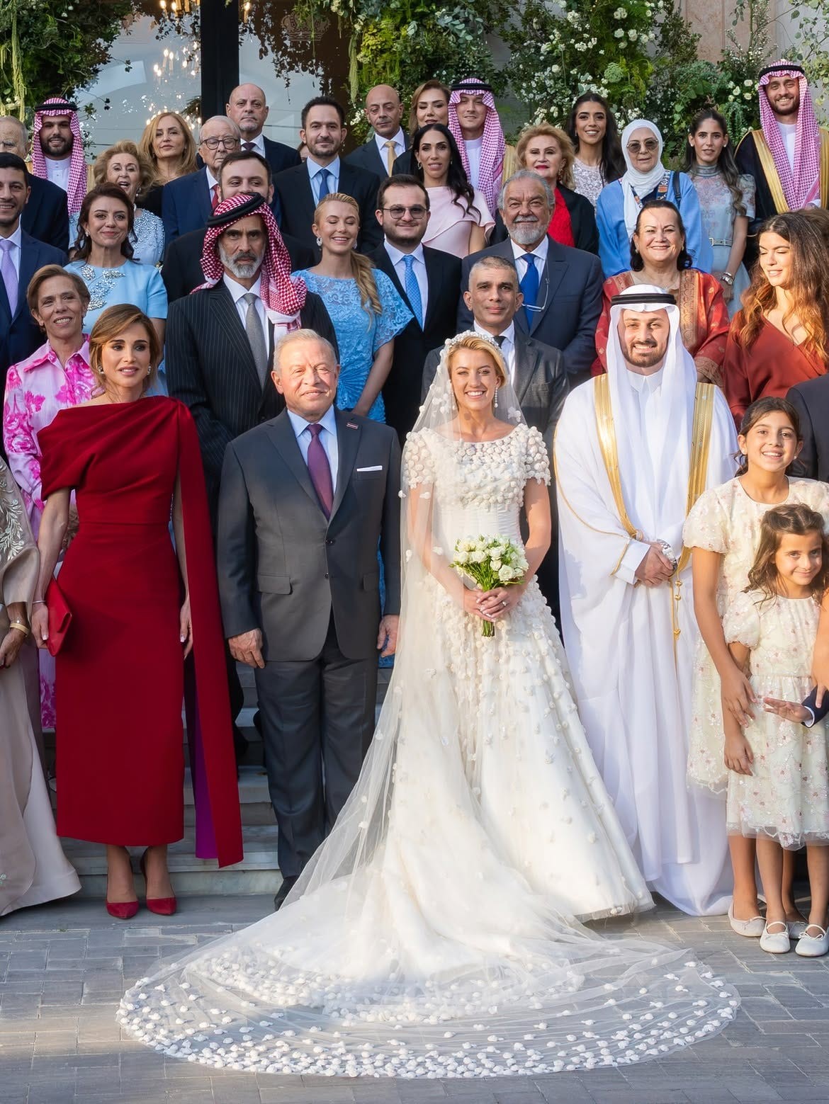 A large group of people, including the bride and groom, posing together at a wedding celebration.