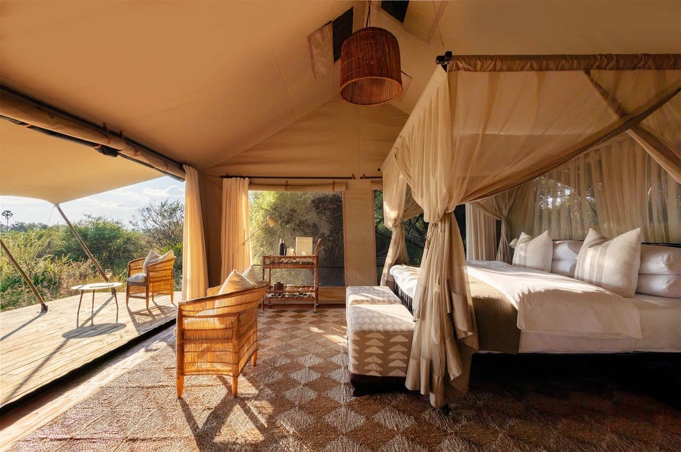 Nkasa Linyanti lodge Natural Selection Namibia Luxurious tented accommodation featuring a bedroom, seating area, and scenic outdoor view.