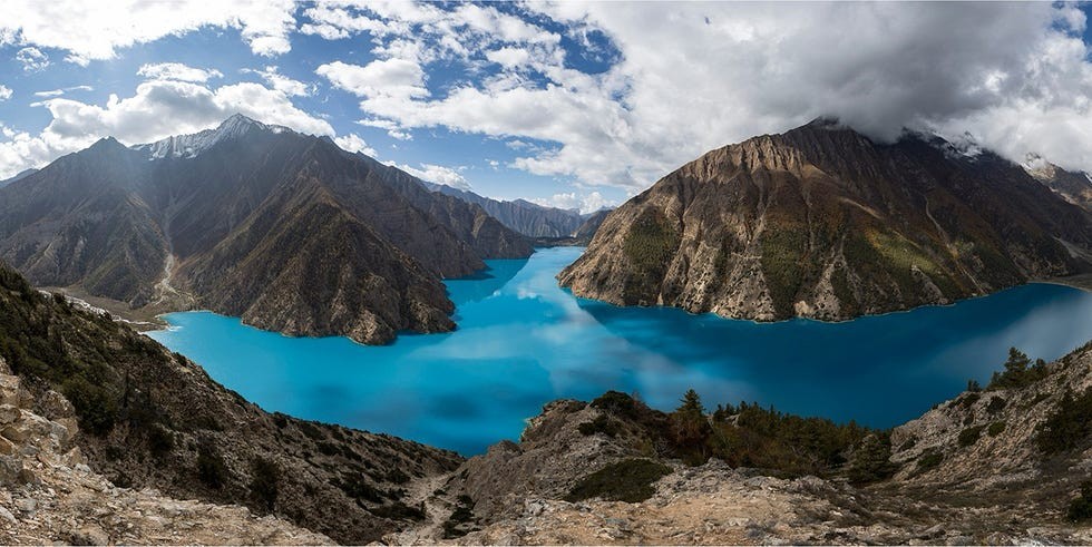 Shey Phoksunso National Park Nepal Stunning panoramic view of a turquoise lake surrounded by mountains and dramatic clouds.