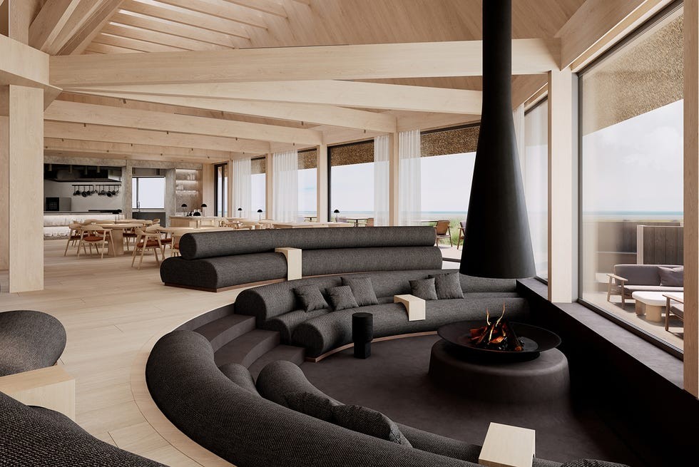 Eha wellness retreat on Hiiumaa island Estonia Modern lounge interior featuring dark curved sofas, a central fire pit, and large windows with ocean views.