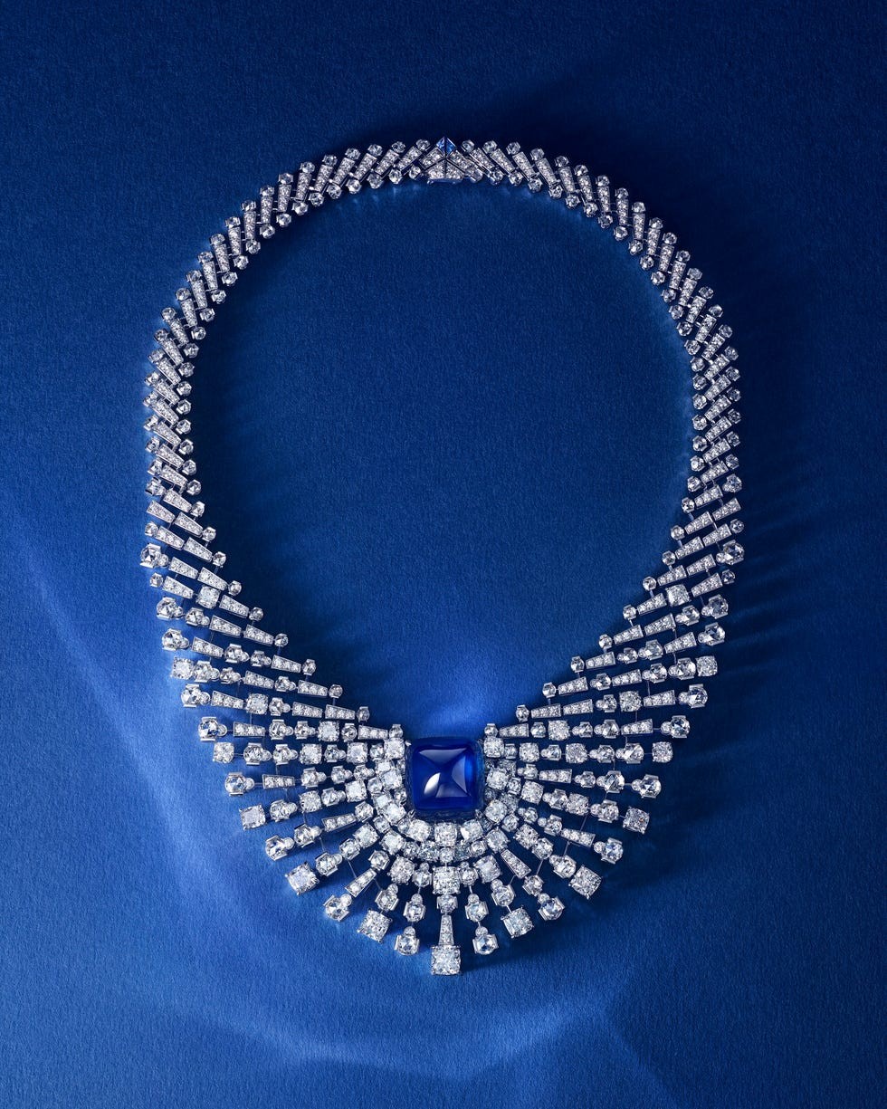 A luxurious diamond necklace with a central blue gemstone on a deep blue background.