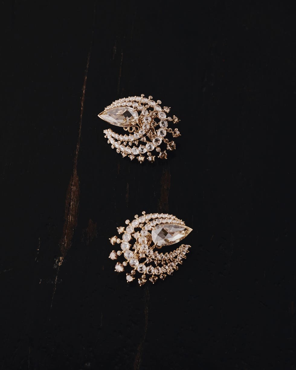 Elegant gold and crystal earrings with intricate design on a dark background.