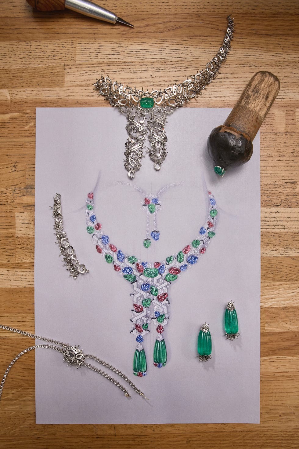 Jewelry design sketch with colorful gemstones and silver elements, including a necklace, earrings, and design tools.
