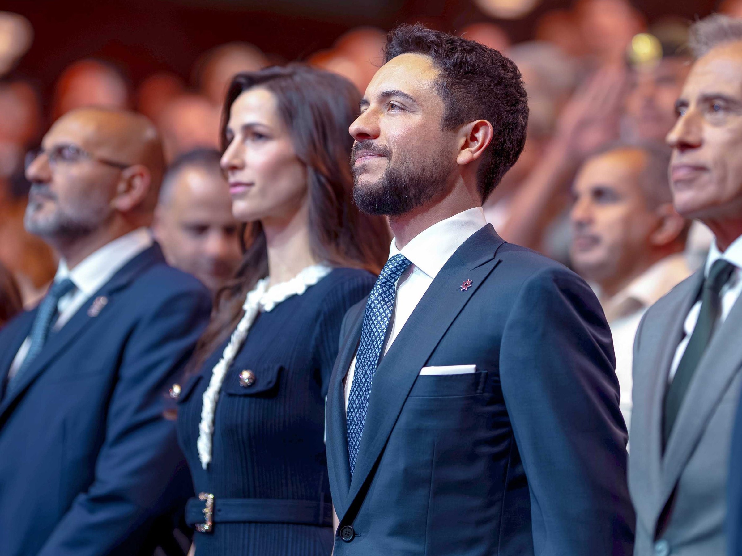 A group of individuals dressed in formal attire standing together, focused on a presentation or event.