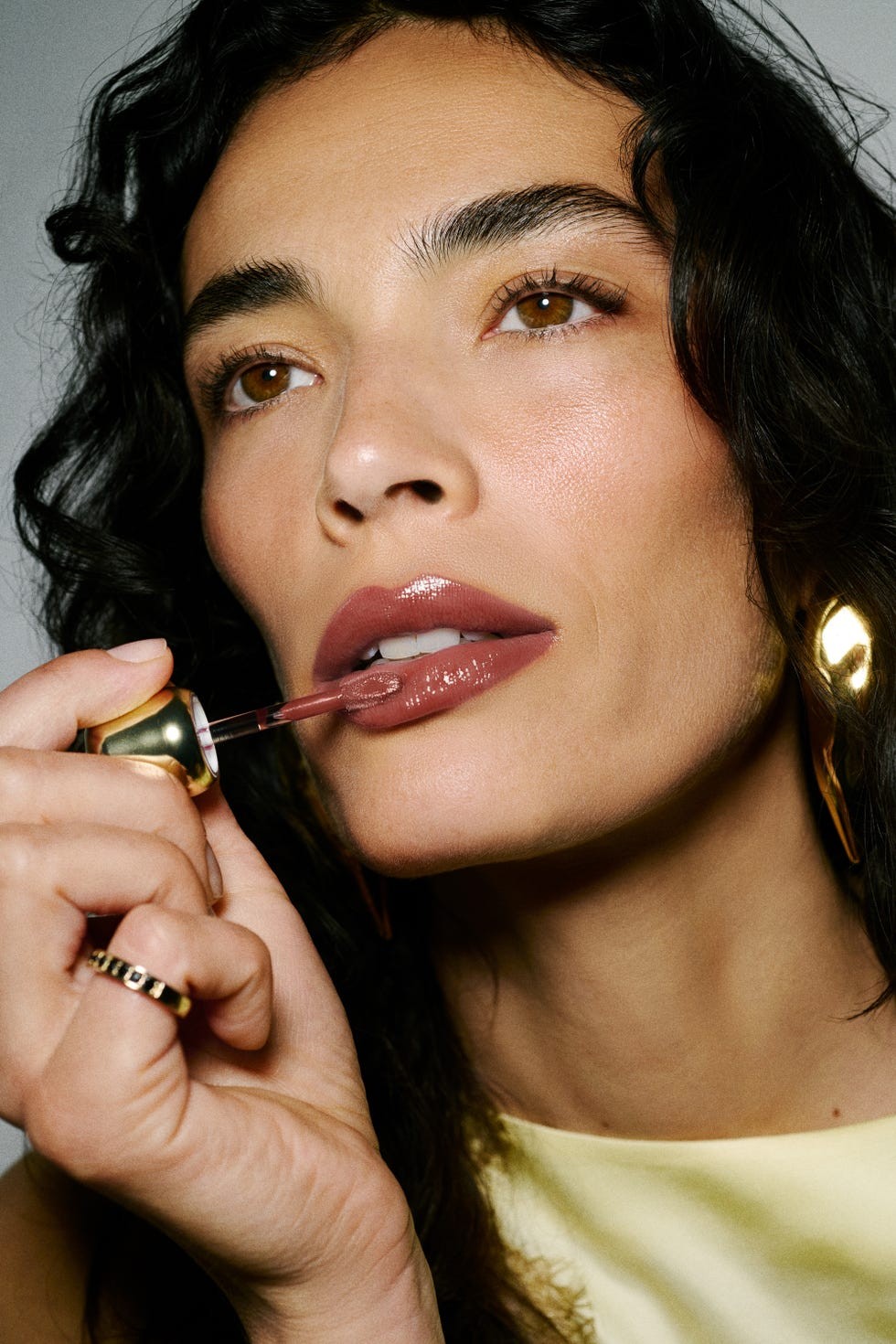 person applying lipstick with glossy finish.