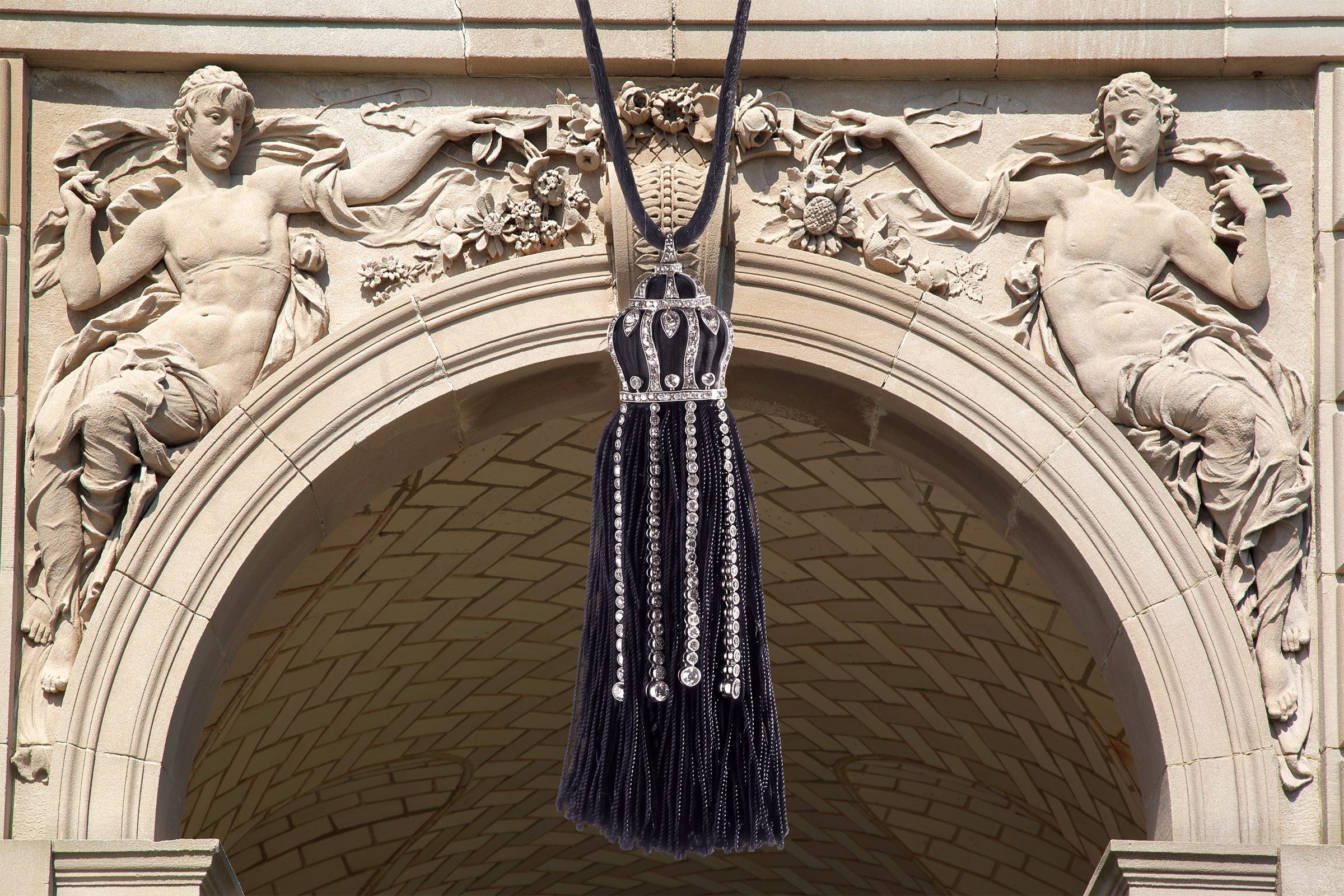 A stylish black dress with intricate beading displayed within an ornate stone archway.