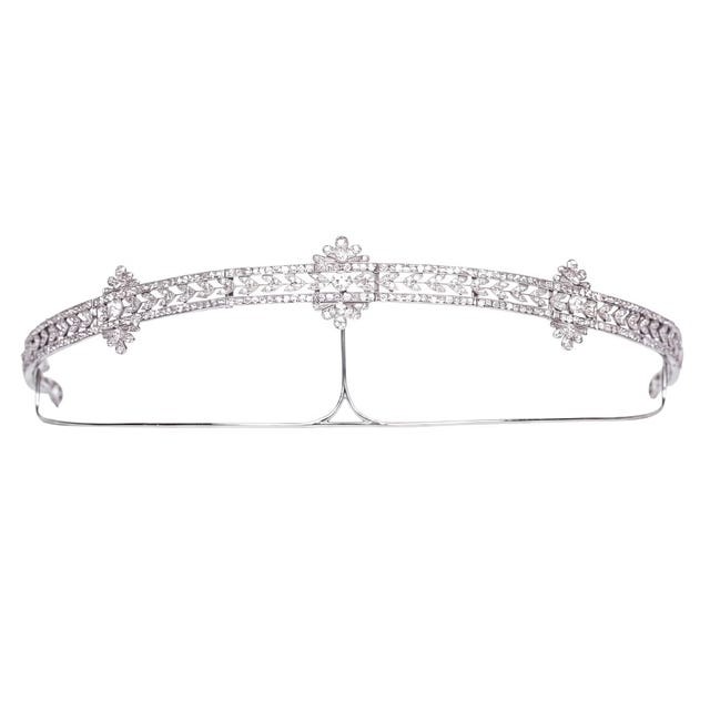 Delicate silver tiara with intricate floral design and sparkling gemstones.