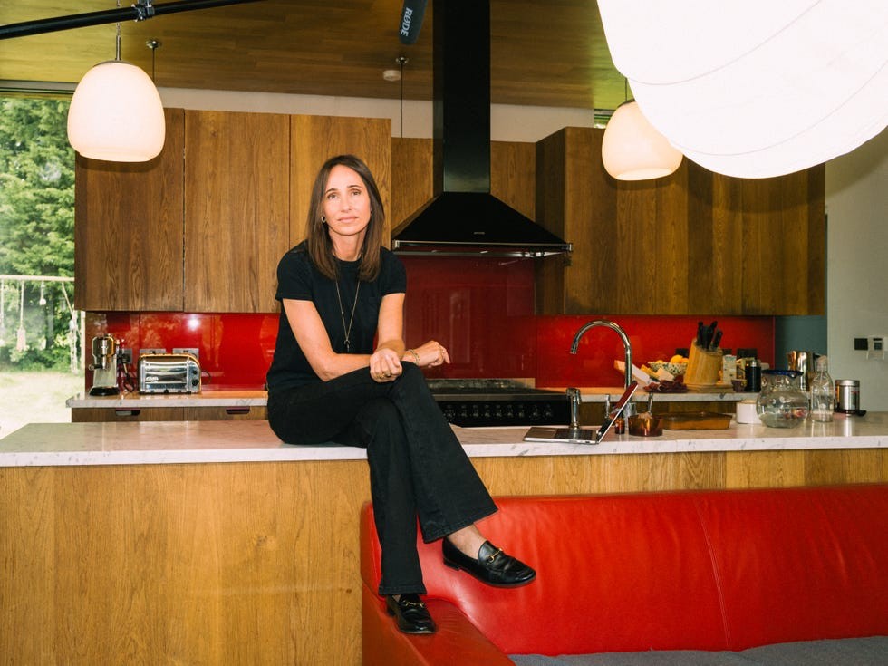 person sitting on a kitchen counter with wooden cabinets and red backsplash