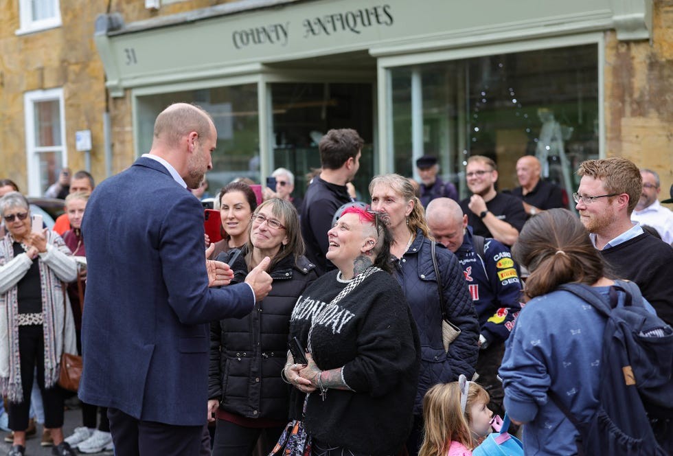 A group of people interacting and smiling during a public event outside County Antiques shop.