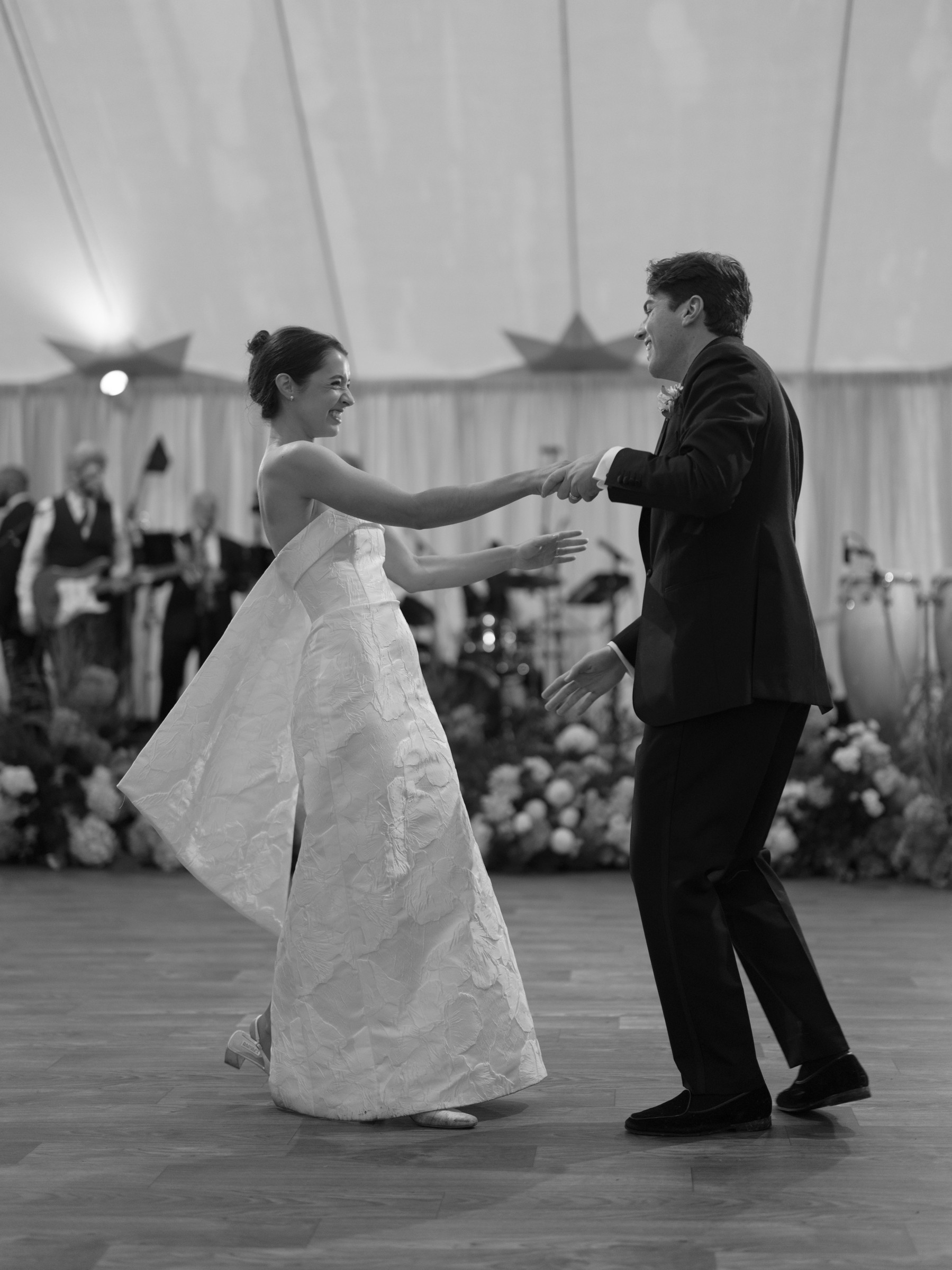 A couple joyfully dancing in elegant attire during a wedding celebration.