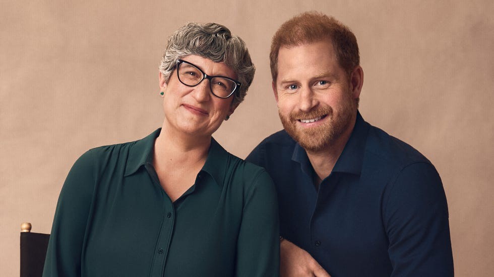 Two smiling individuals with light backgrounds, one wearing glasses and the other with a beard, seated together.
