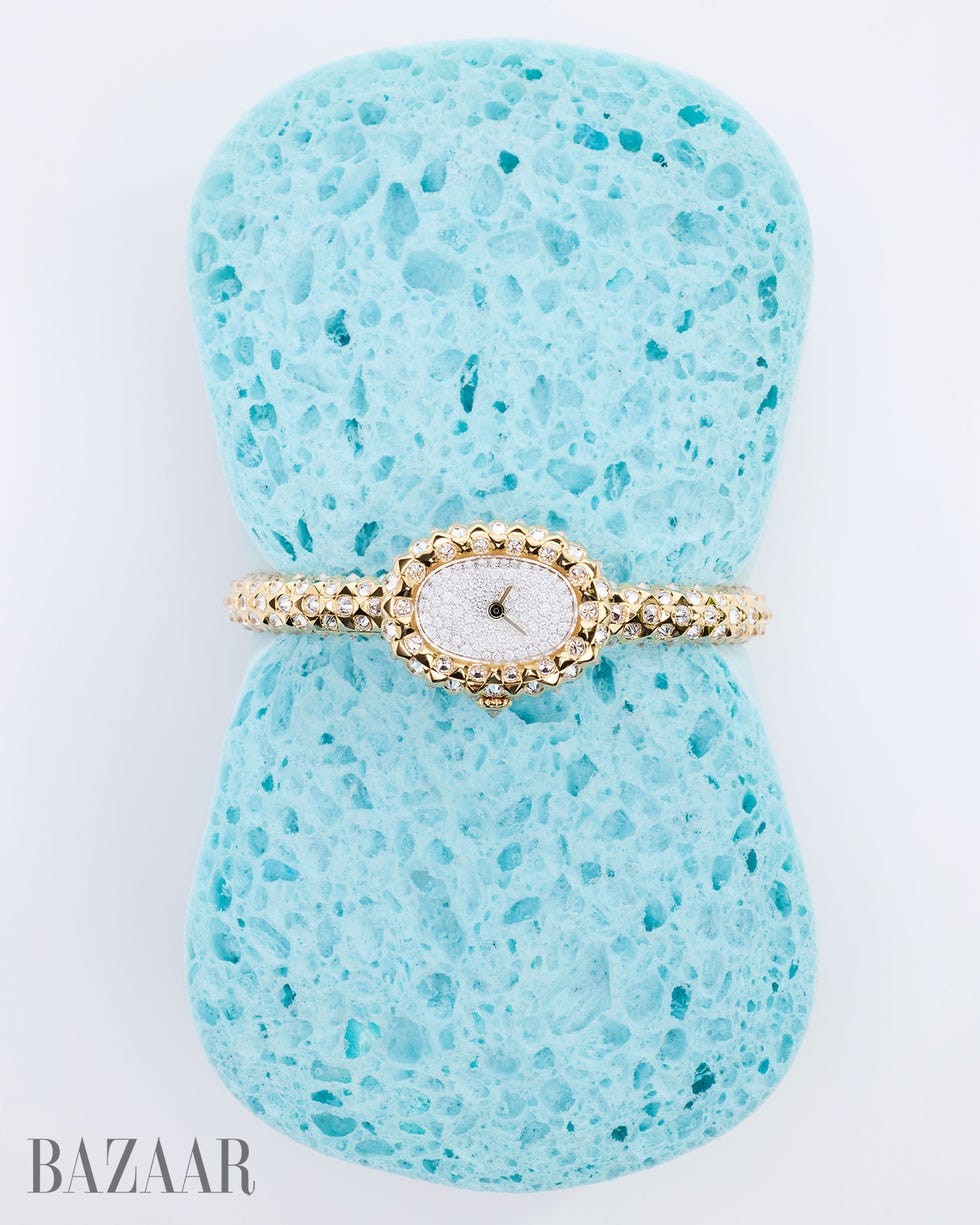 Gold watch resting on a textured blue sponge background.