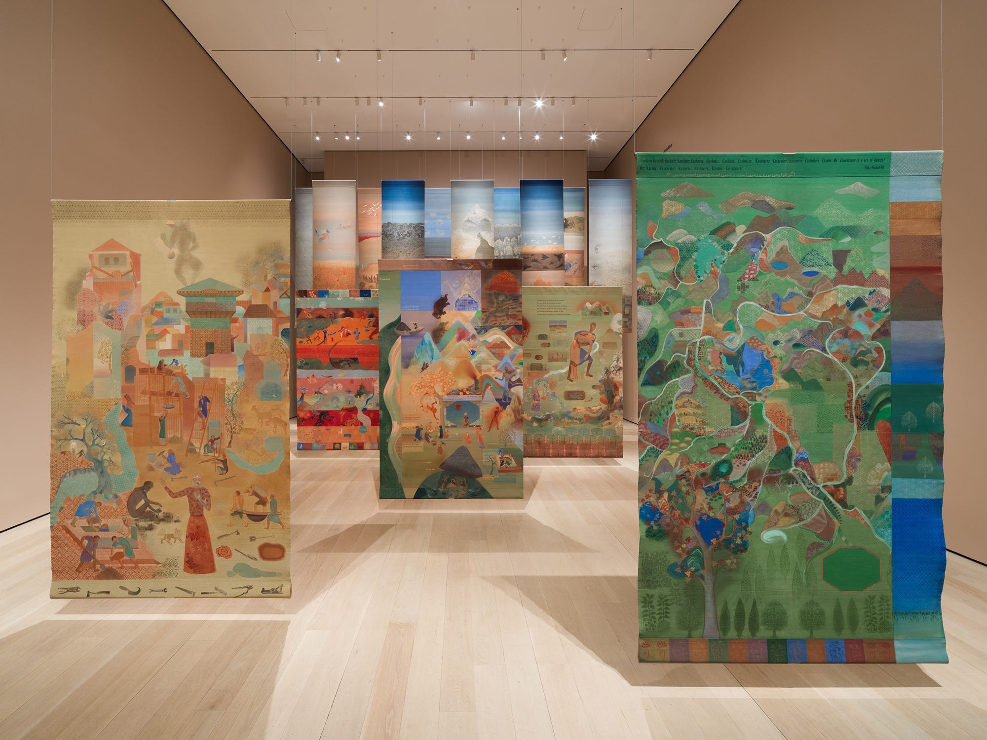 Colorful textile murals displayed in an art gallery, showcasing various landscapes and scenes.