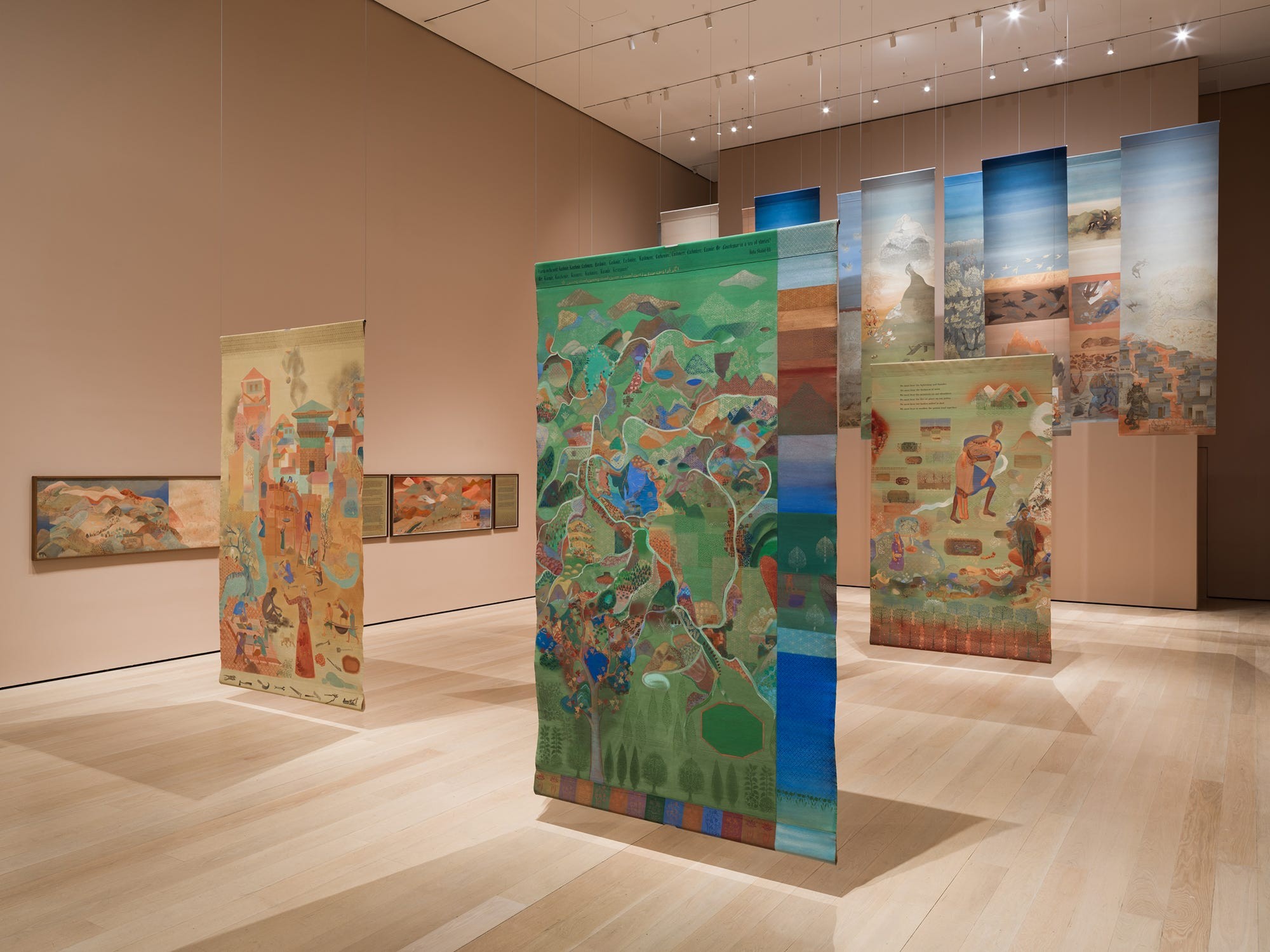 Colorful art installations on display in a contemporary gallery, featuring various hanging banners and wall pieces.
