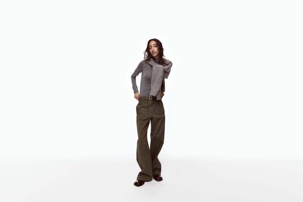 A model poses in a gray sweater and olive green pants against a plain white background.