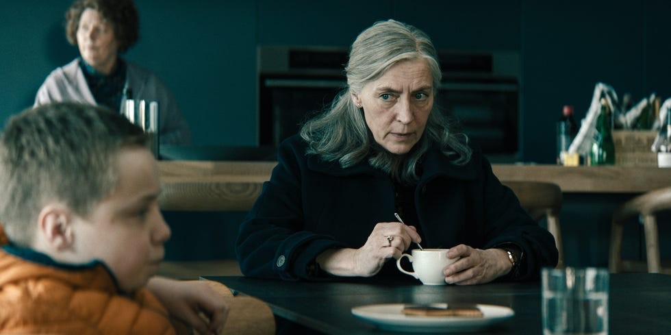 A concerned woman stirring coffee while sitting across from a boy in a cafe setting.
