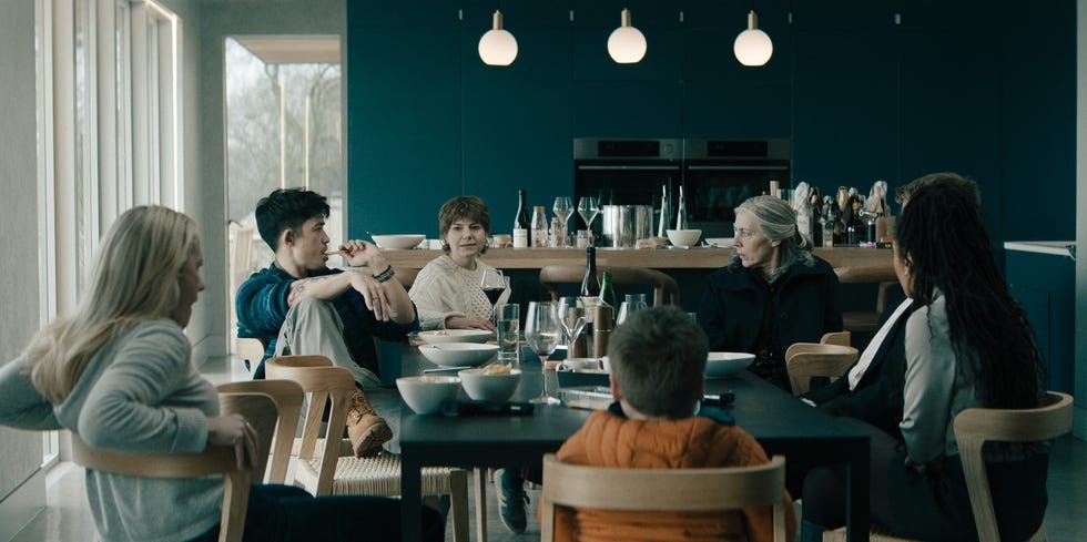 A group of people seated around a table in a modern dining area, engaged in conversation.
