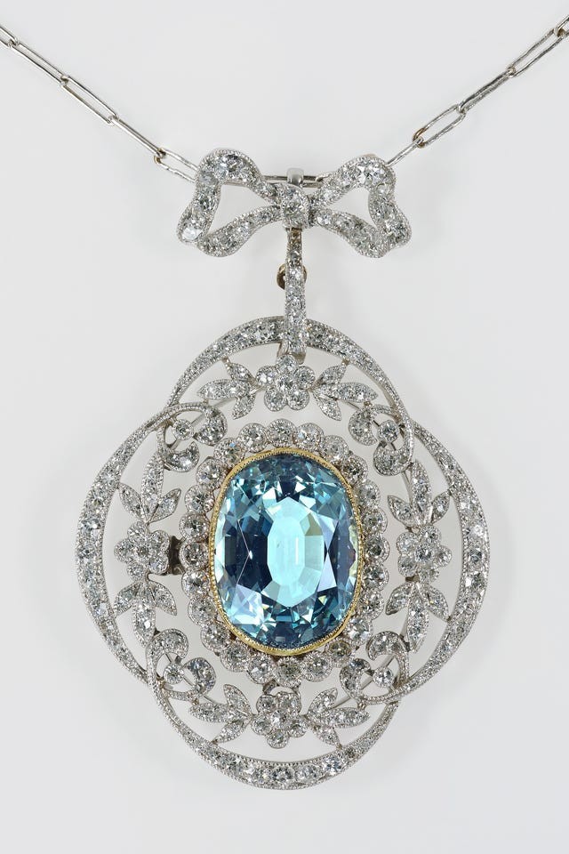 Vintage silver necklace with intricate floral design and a large oval aquamarine stone centerpiece.