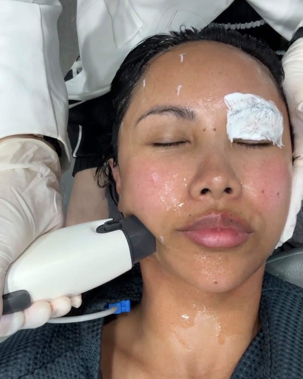 Woman receiving a facial treatment with a device while relaxing in a spa setting.
