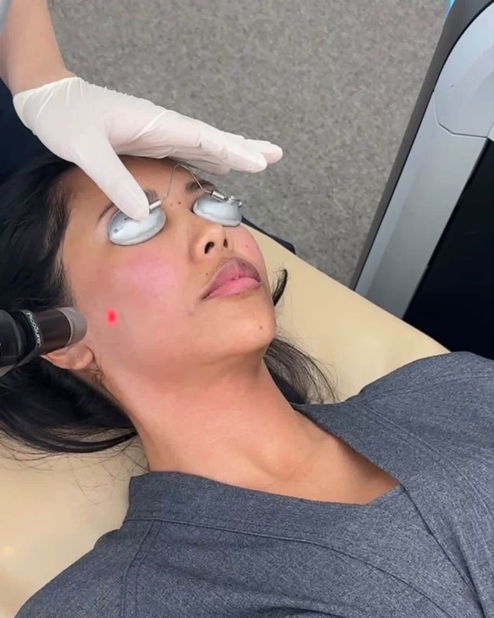 Woman receiving a facial treatment with protective goggles and equipment in a clinical setting.