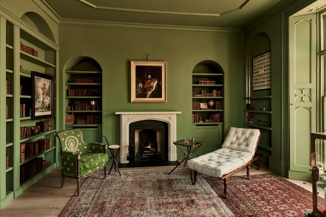 Elegant green room featuring a fireplace, bookshelves, vintage furniture, and decorative elements.