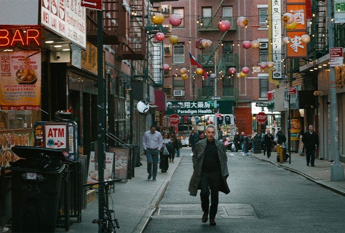 Busy street scene in Chinatown with people walking and colorful lanterns overhead.