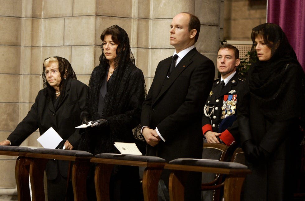 A group of individuals in black attire attending a solemn ceremony, expressing grief and mourning.