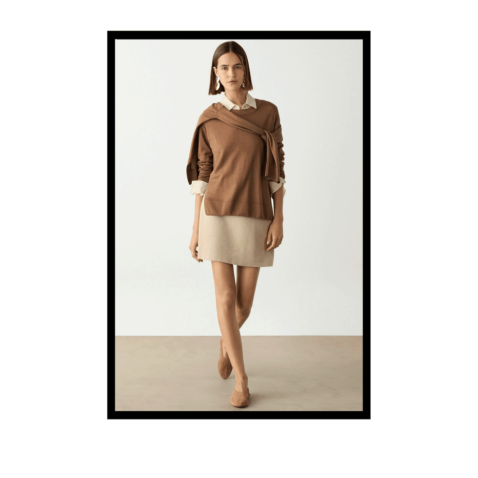 Model wearing a brown sweater over a beige dress, posing against a neutral background.