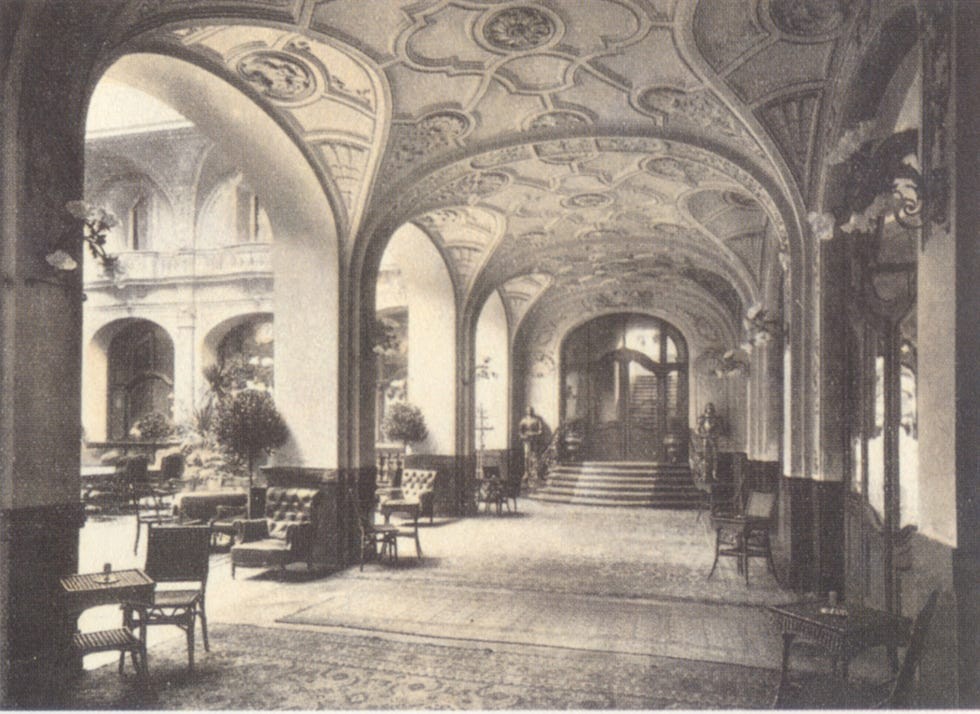 Luxurious historic hallway with ornate arches, elegant furniture, and decorative ceilings.