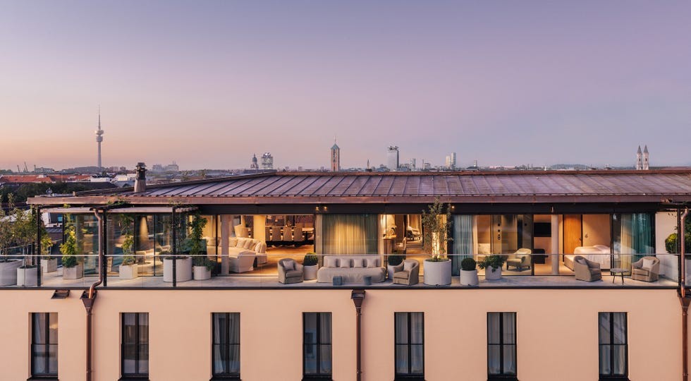 Rooftop lounge overlooking a city skyline at dusk with modern furniture and greenery.