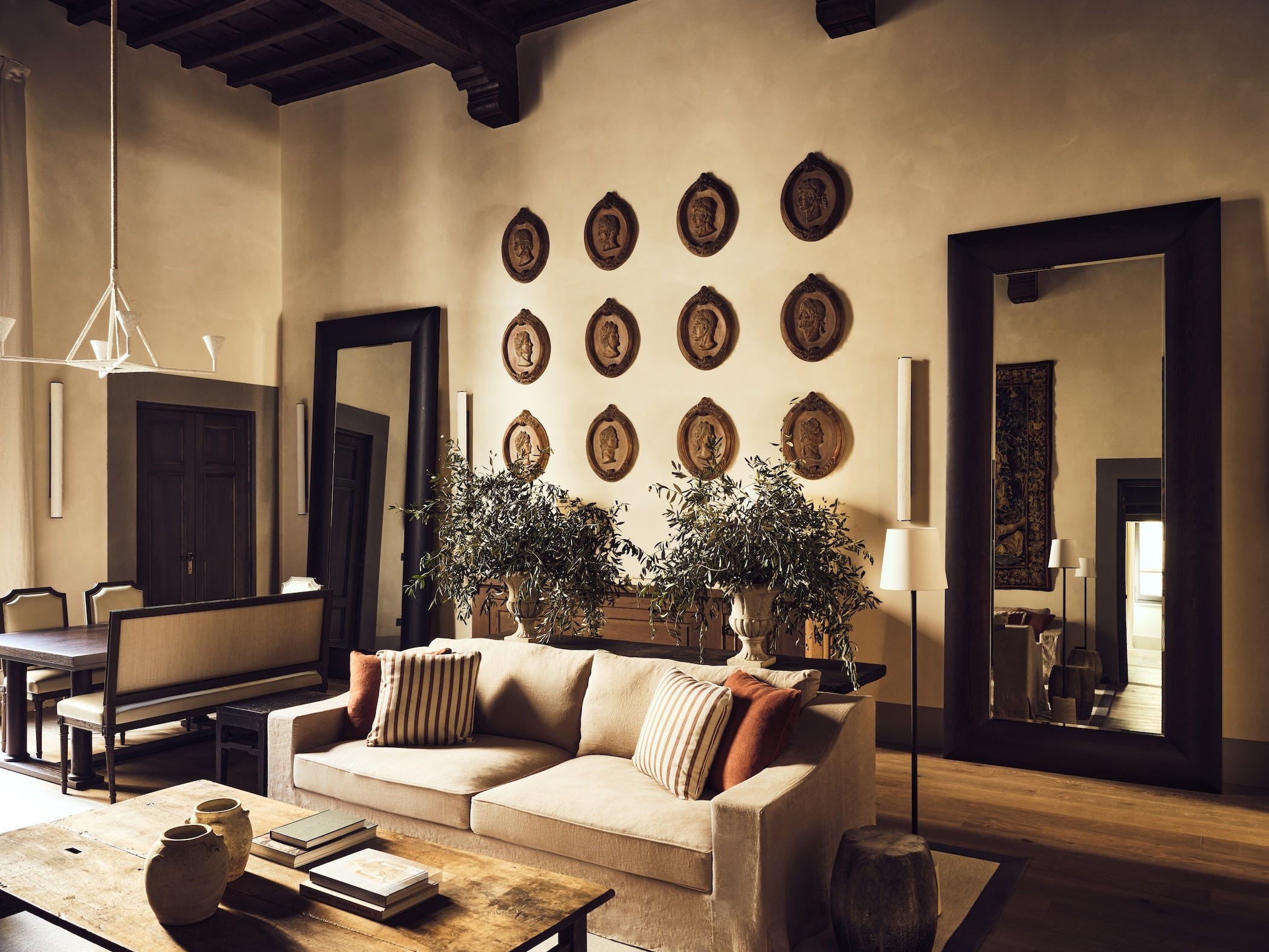 Modern living room featuring a beige sofa, decorative wall plates, large mirrors, and elegant furnishings.