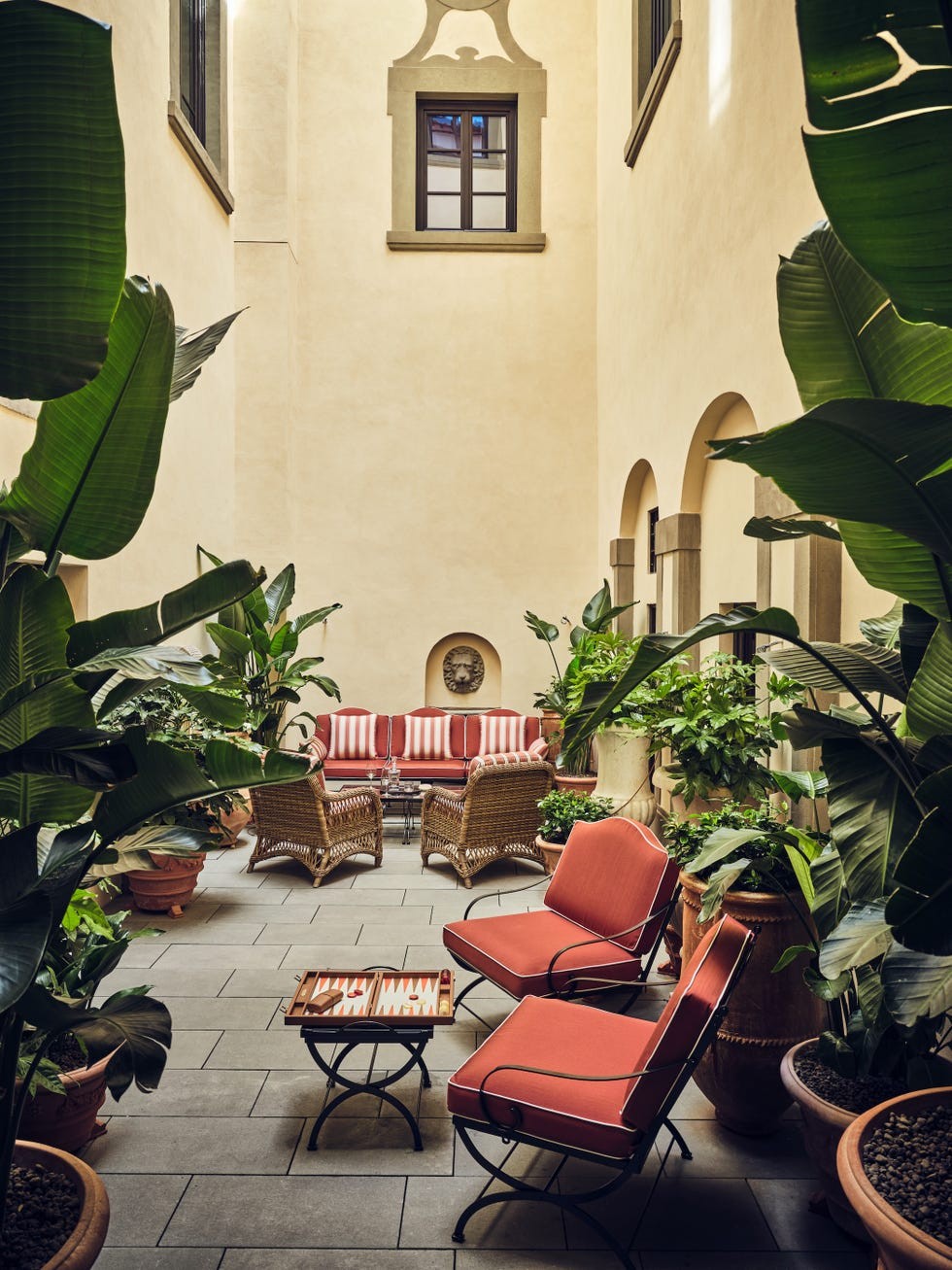Relaxing indoor garden lounge with potted plants, striped sofas, and red armchairs.