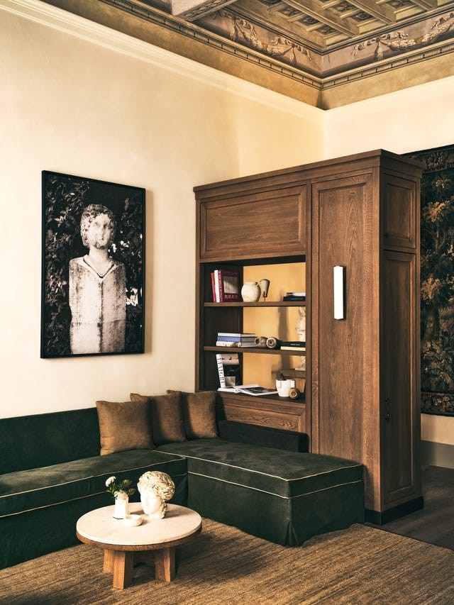 Cozy living room with green sofa, marble coffee table, and a wall art featuring a classical statue.