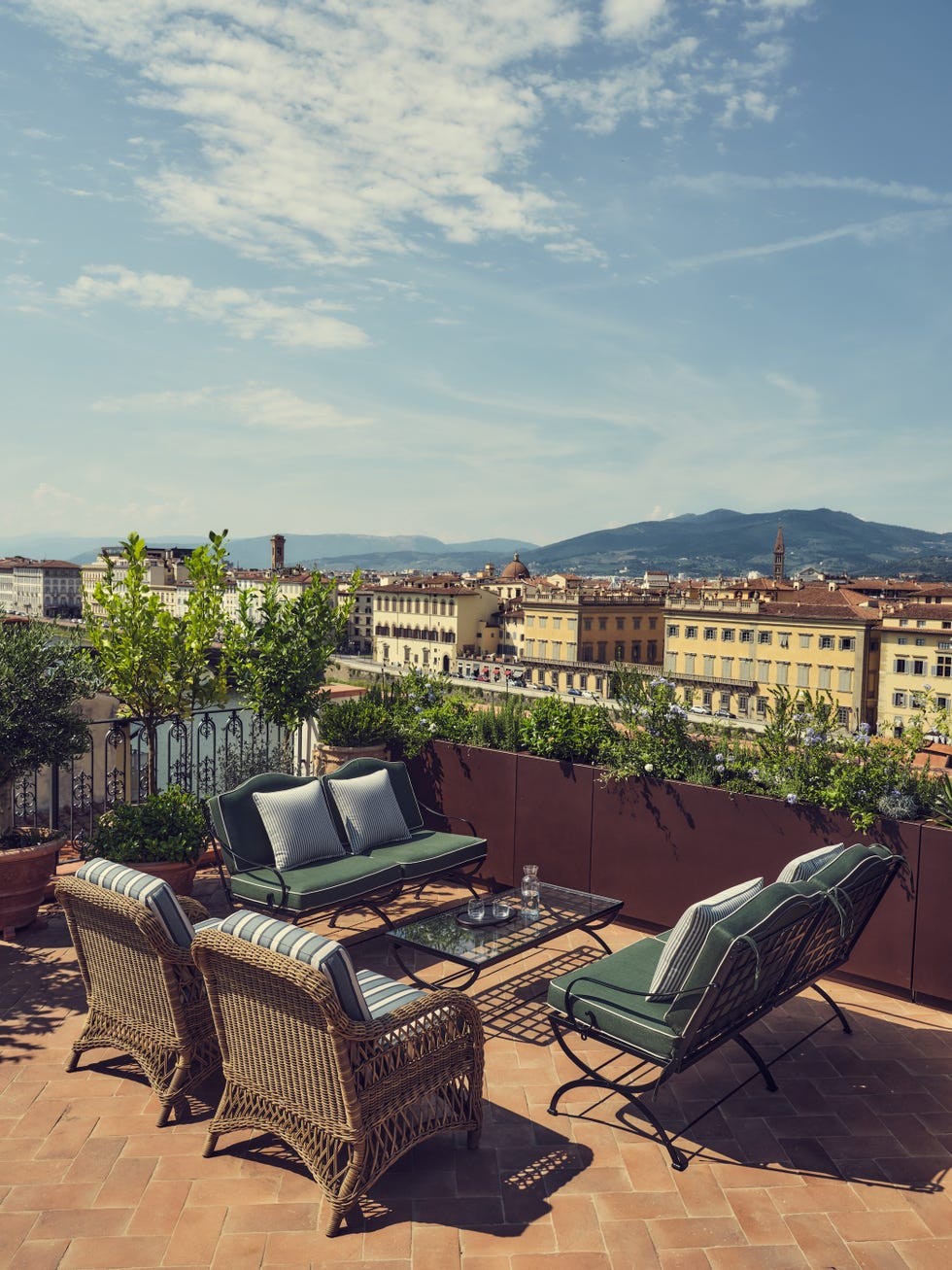 Rooftop seating area overlooking a cityscape with a blue sky and mountains in the distance.