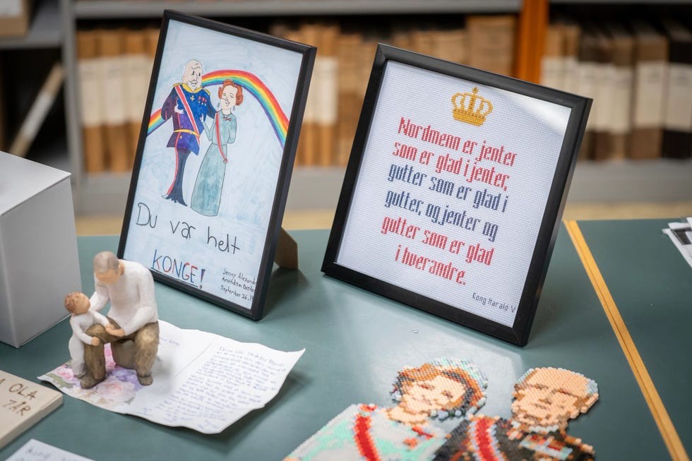 Artwork featuring framed drawings and text promoting inclusivity and royal themes, alongside a figurine of a parent and child.