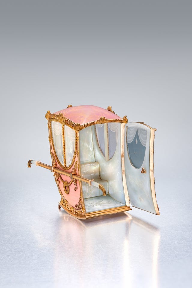 Decorative miniature carriage with an open door and elegant interior details.