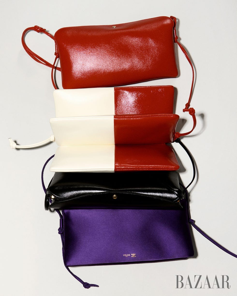 Stack of four stylish handbags in red, white, black, and purple against a neutral background.